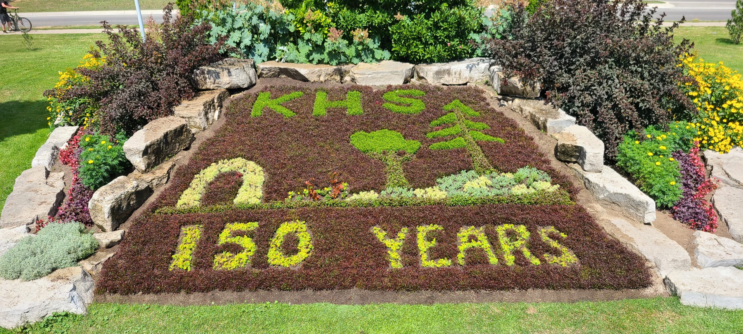 a garden planted to read KHS 150 Years and an image of an arch and tree