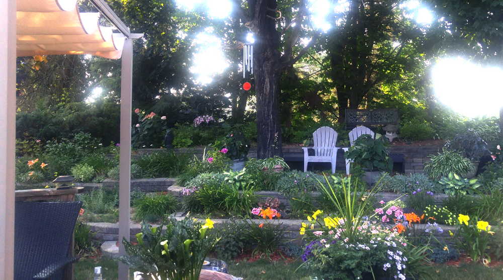 garden with many levels featuring hostas, lilies, and two lounge chairs