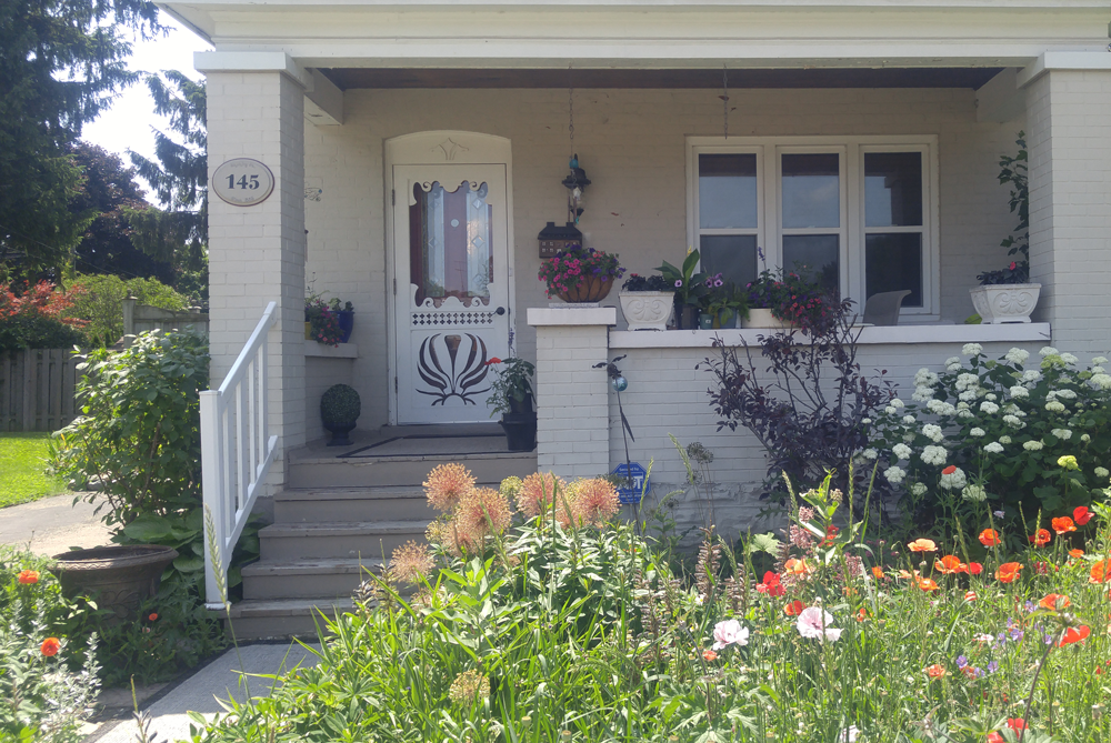 White House with covered porch and blooming summer garden out front